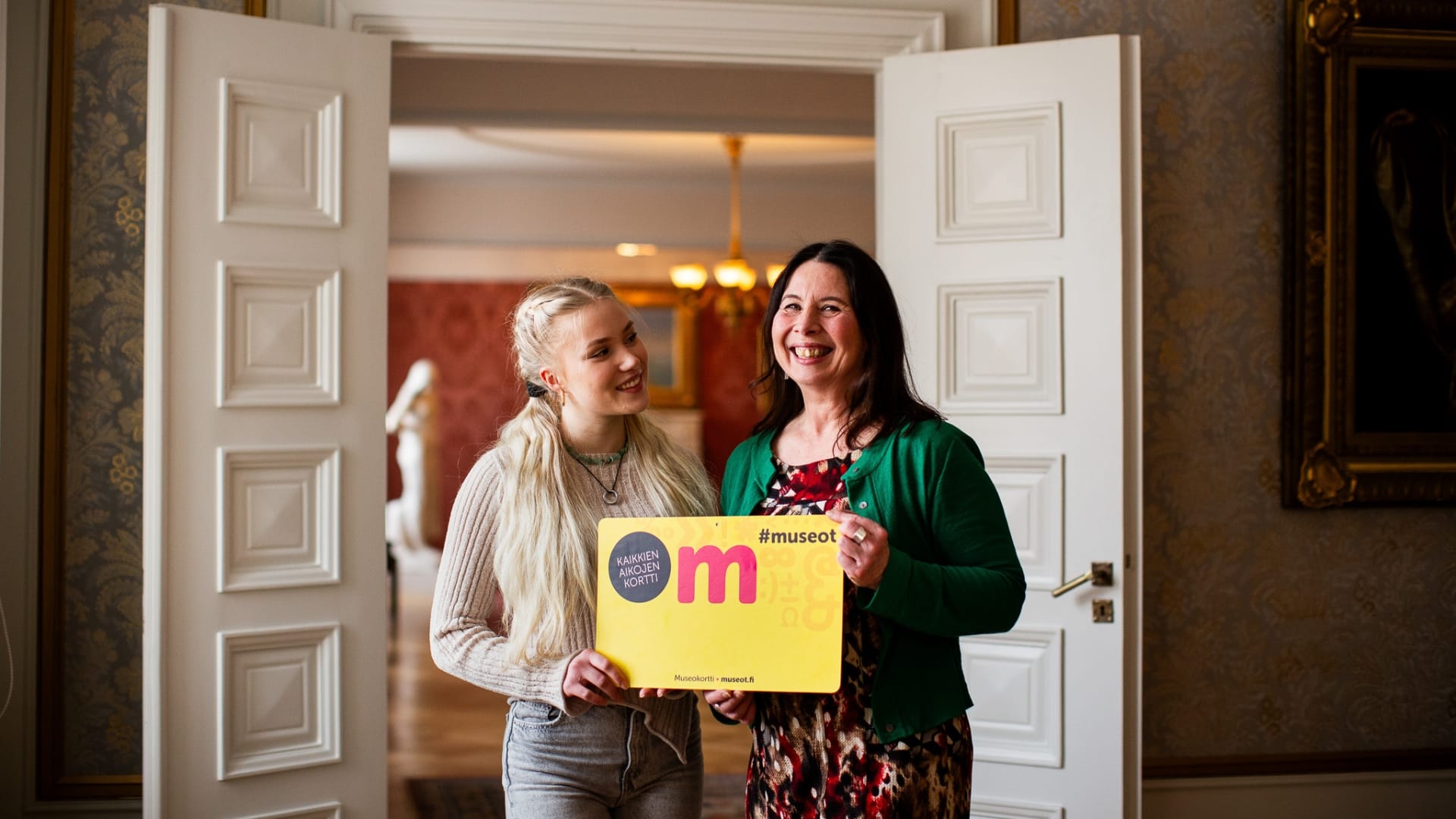 Kaksi henkilöä pitää isoa Museokorttia. Museokortti 10 vuotta!