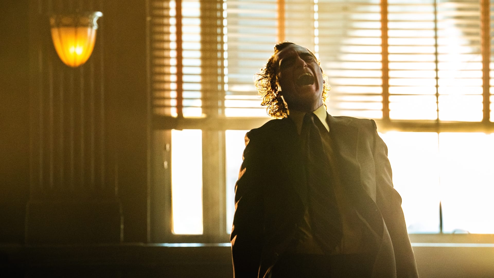 Jokeri eli Joaquin Phoenix nauraa. Mitä kannattaa tietää ennen Joker: Folie à Deux -elokuvan katsomista?