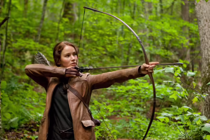 Katniss Everdeen tähtäämässä jousellaan metsässä